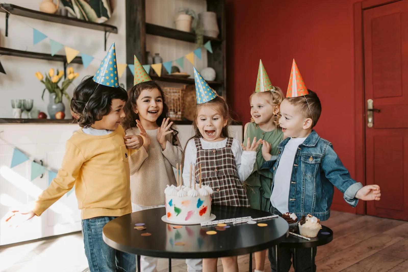 Happy children in party hats celebrating around a cake